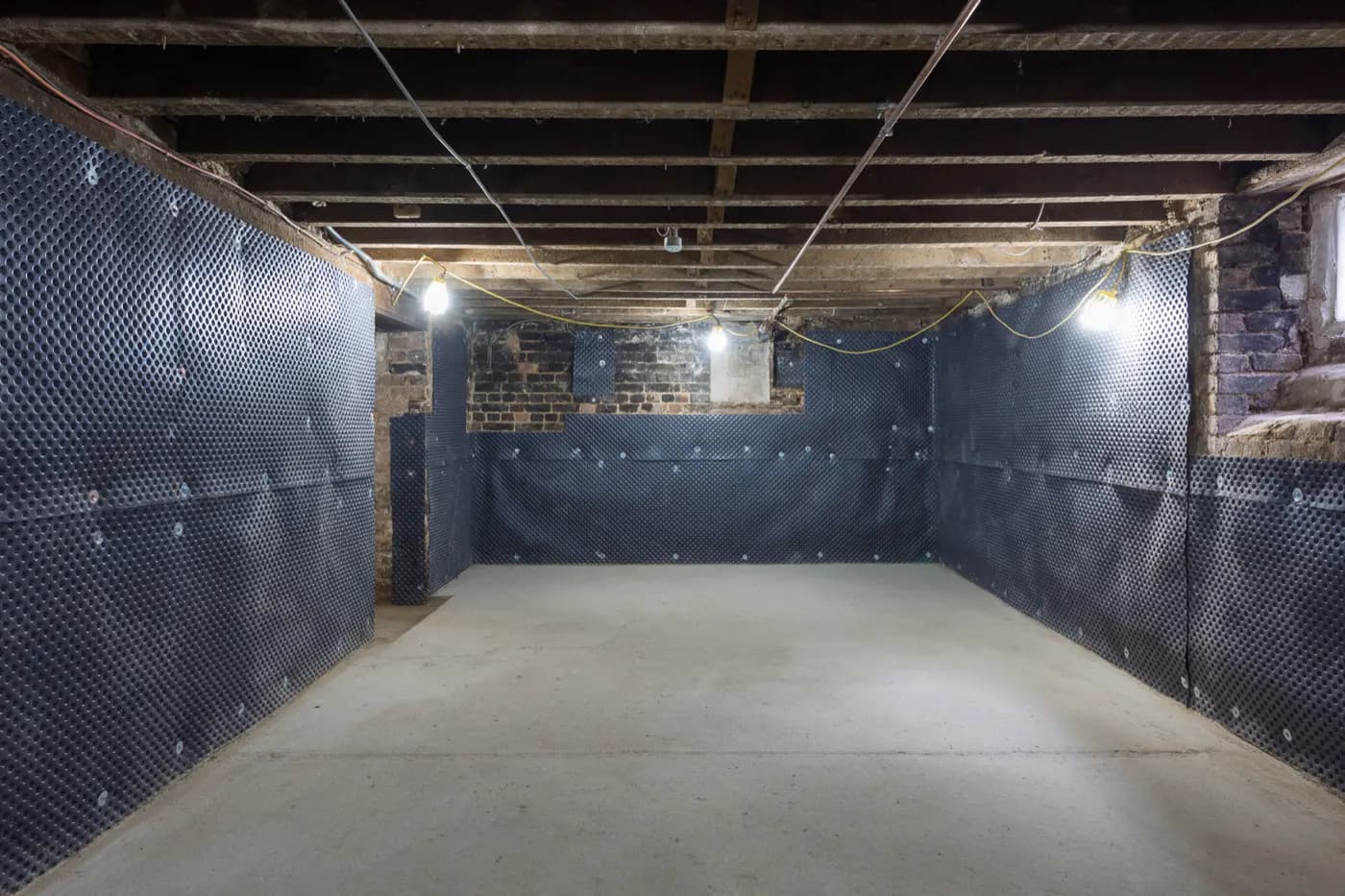 A cellar being converted: walls lined with a studded waterproofing membrane and a new concrete floor