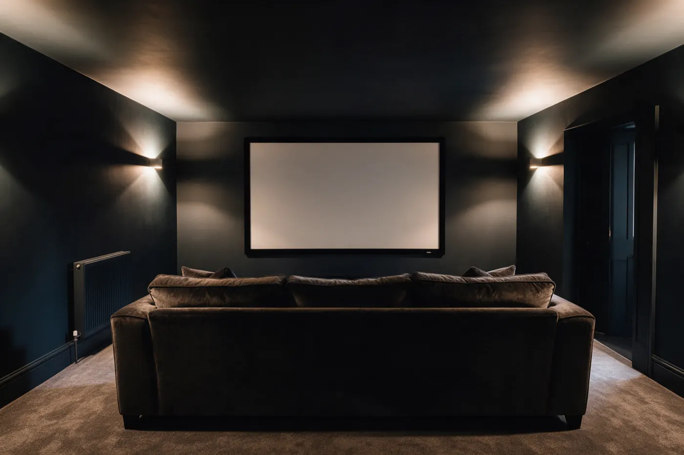 A home cinema room with a projector screen and a large sofa