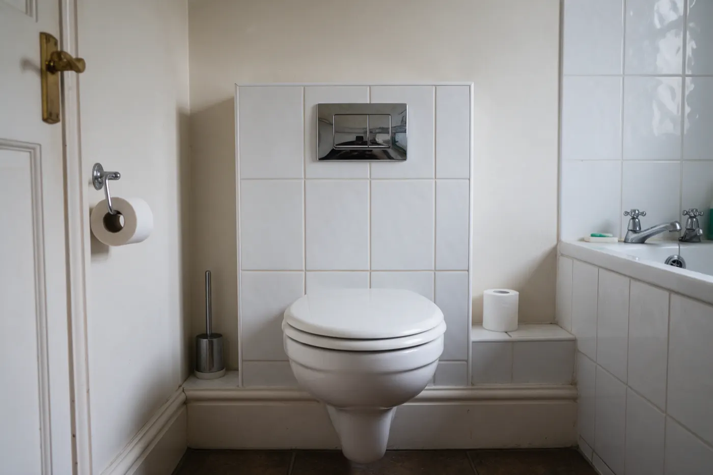 A wall-hung toilet with a flush plate on a boxed-in wall